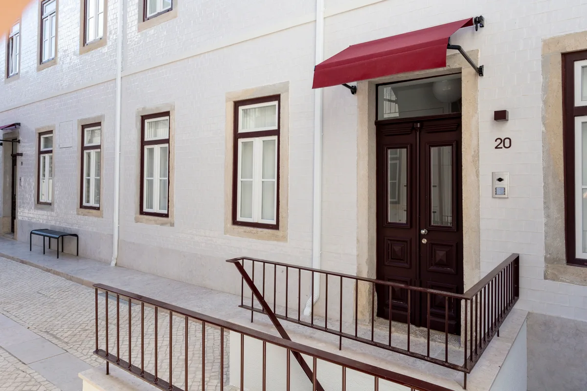 Building entrance with a dark wooden door beneath a red awning.