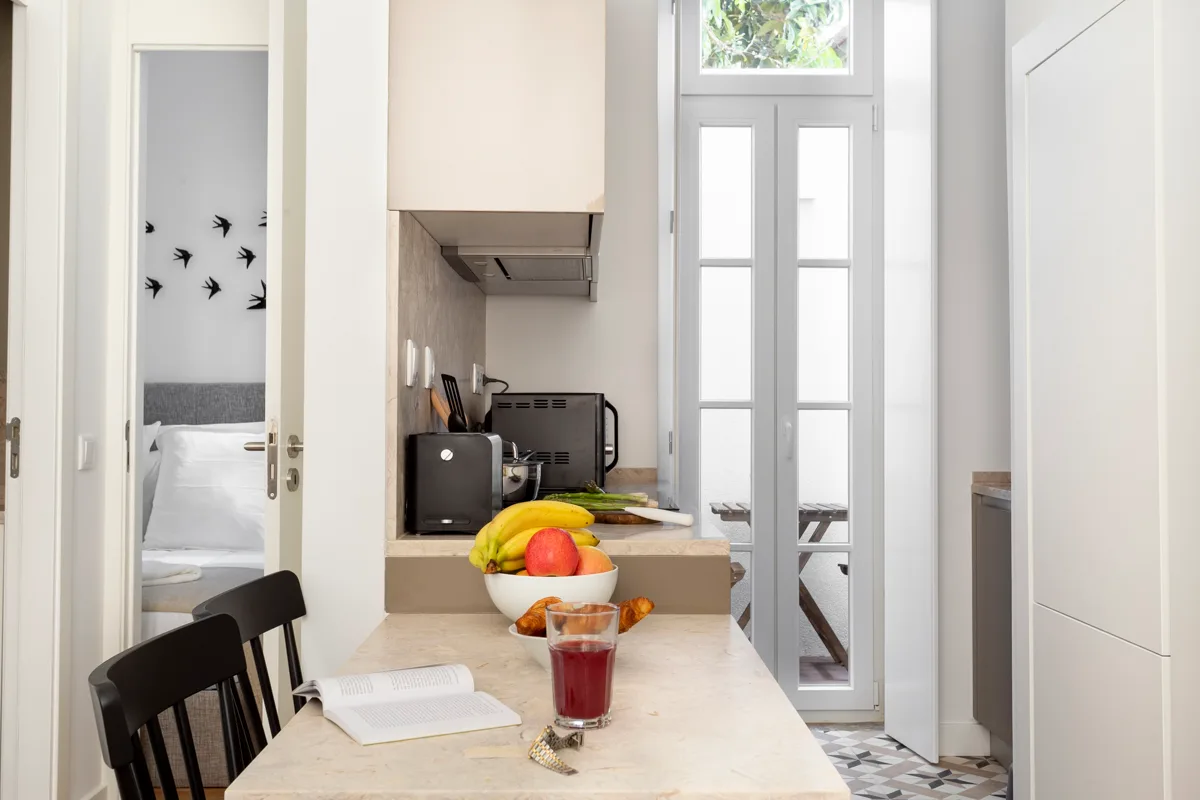A bright kitchen and dining area with a counter, seating, and tall windows.