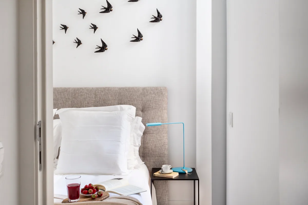 A bedroom with a white bed and bird decorations on the wall.