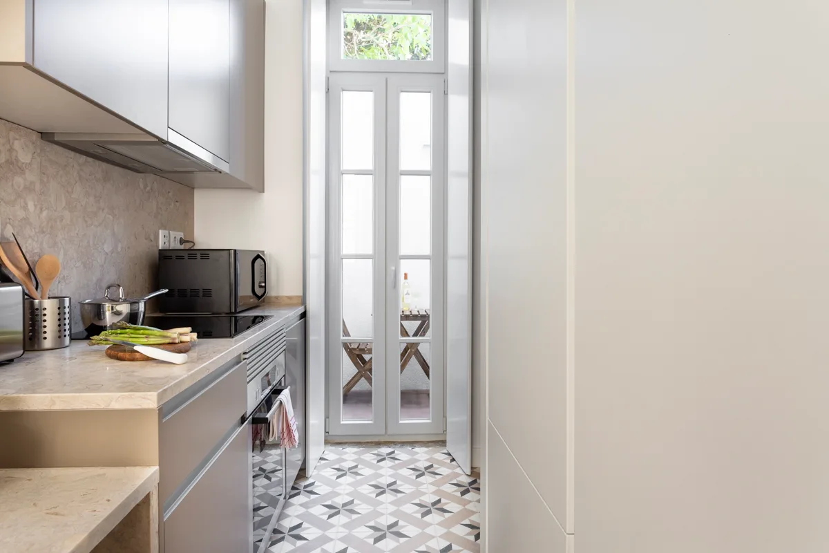 A compact kitchen with a counter and tall glazed doors.