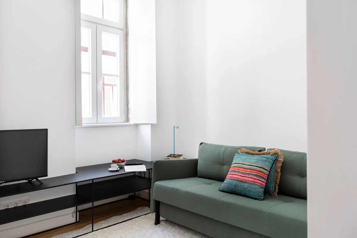 A bright living room with a green sofa and television.