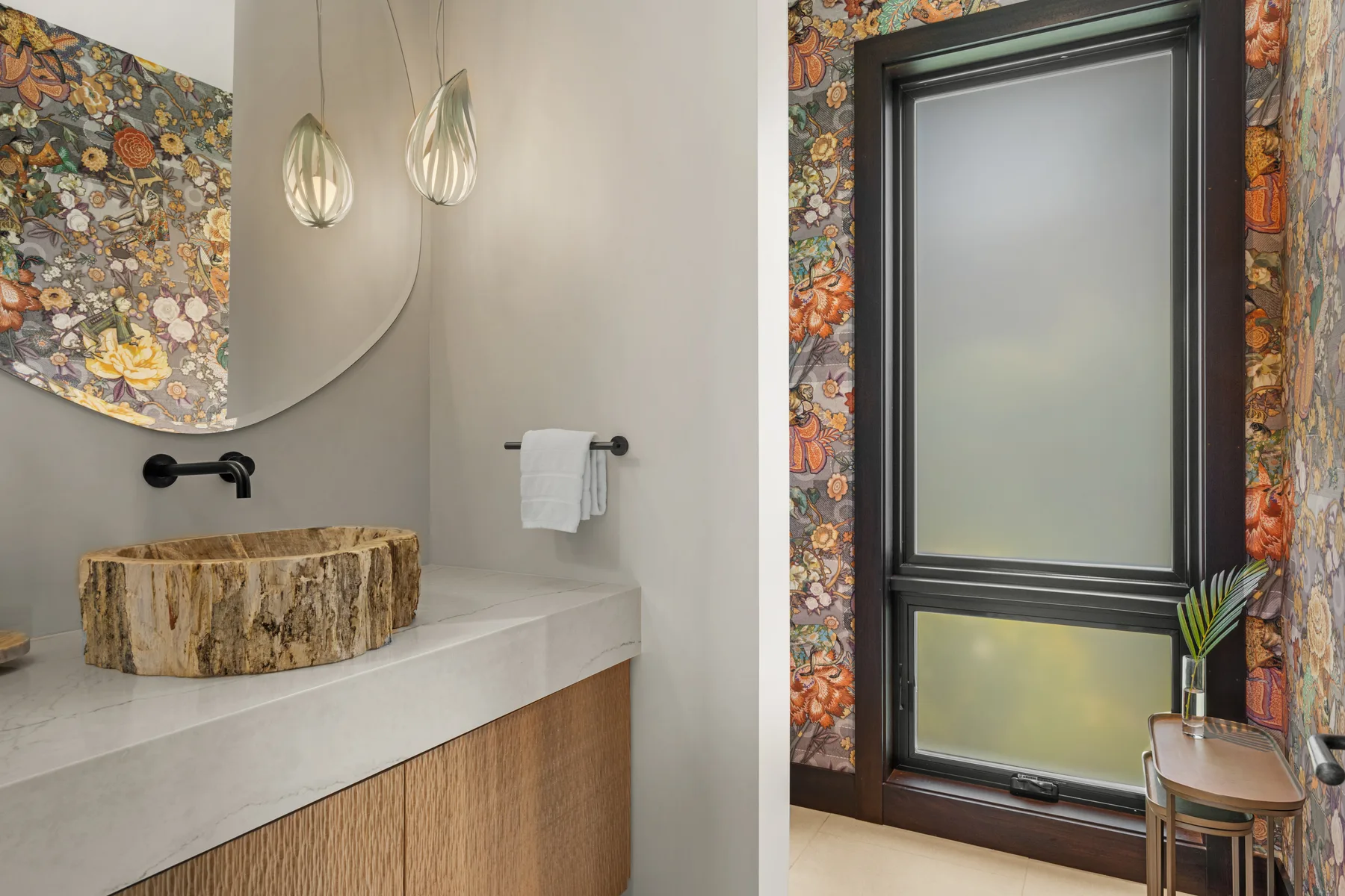 Un tocador de baño con lavabo de piedra junto a una ventana alta.