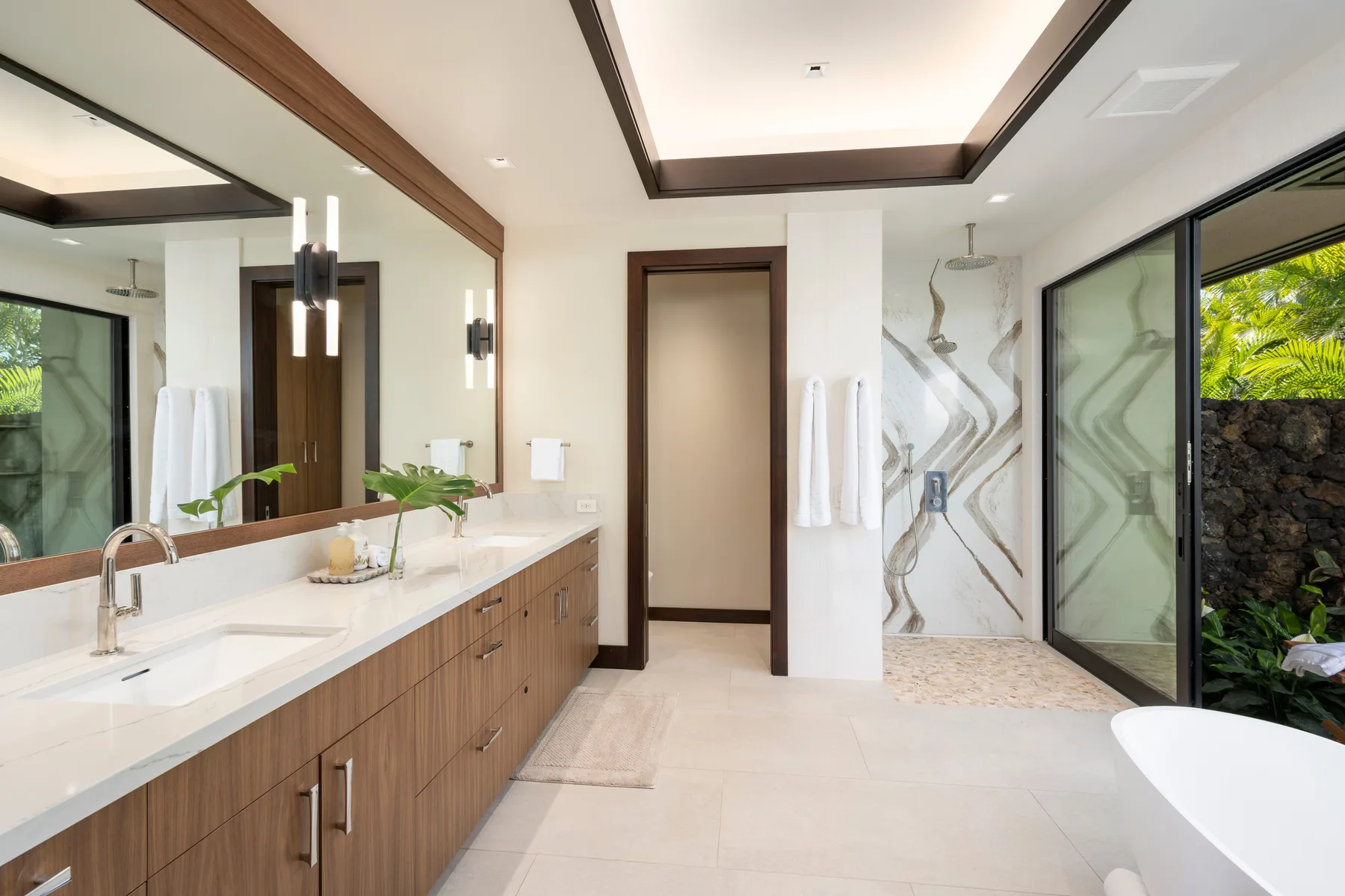 Un baño moderno con un lavabo largo, una ducha de vidrio y una bañera exenta.