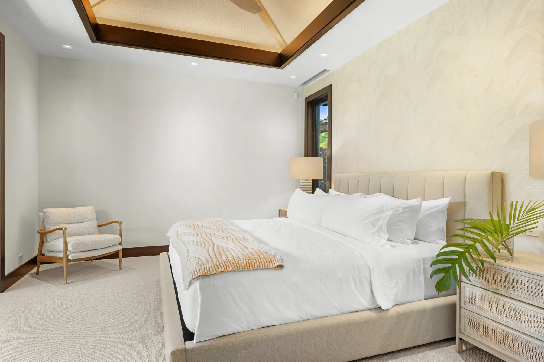 Un dormitorio luminoso con una cama grande y un sillón tapizado.