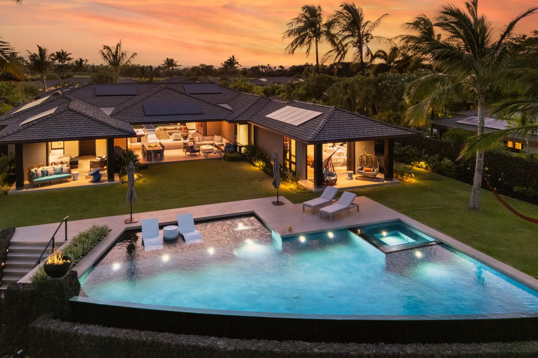 Una casa moderna da a una piscina y un jardín al atardecer.