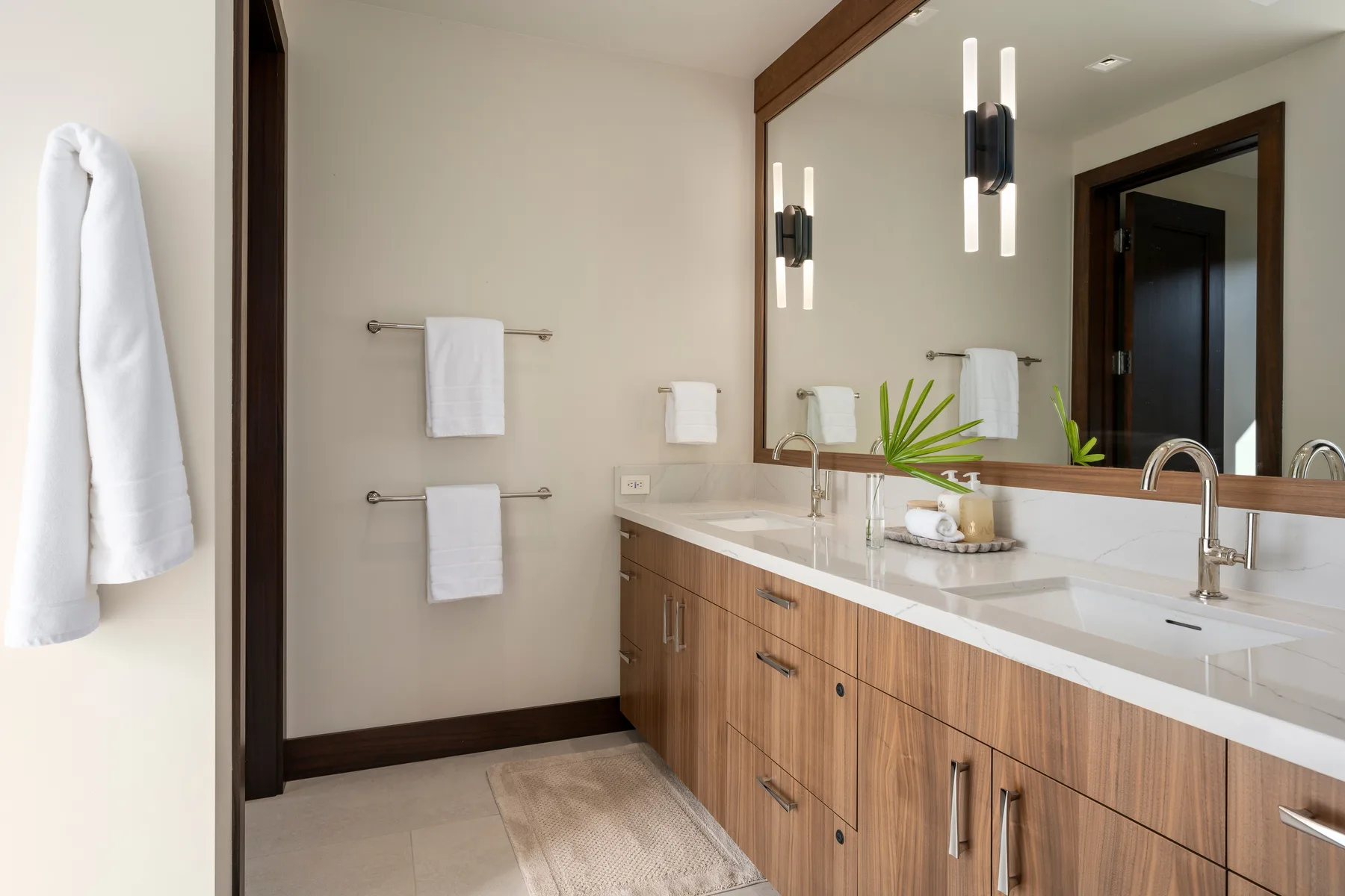 Un lavabo de baño con un espejo largo, dos lavamanos y muebles de madera.
