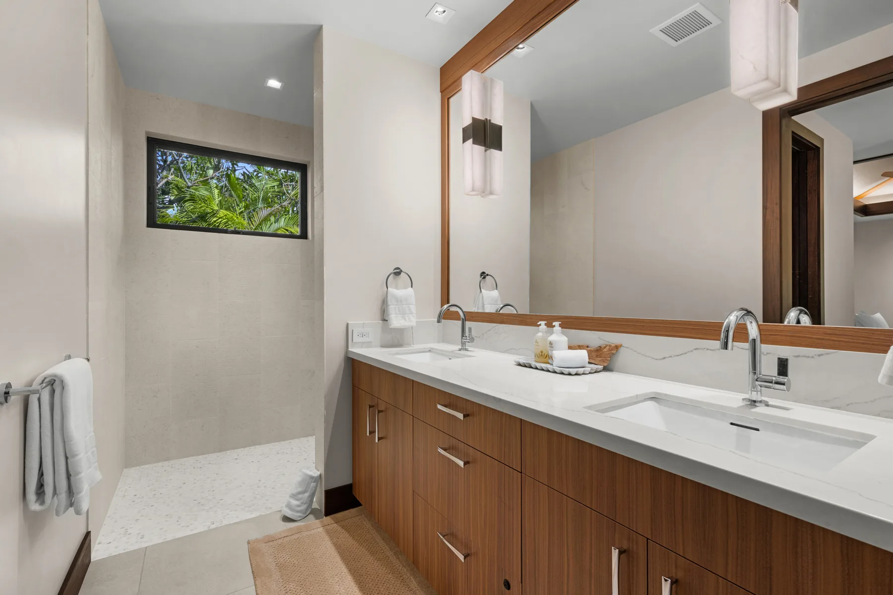 Un baño moderno con un tocador largo, dos lavabos y una ducha a ras de suelo.