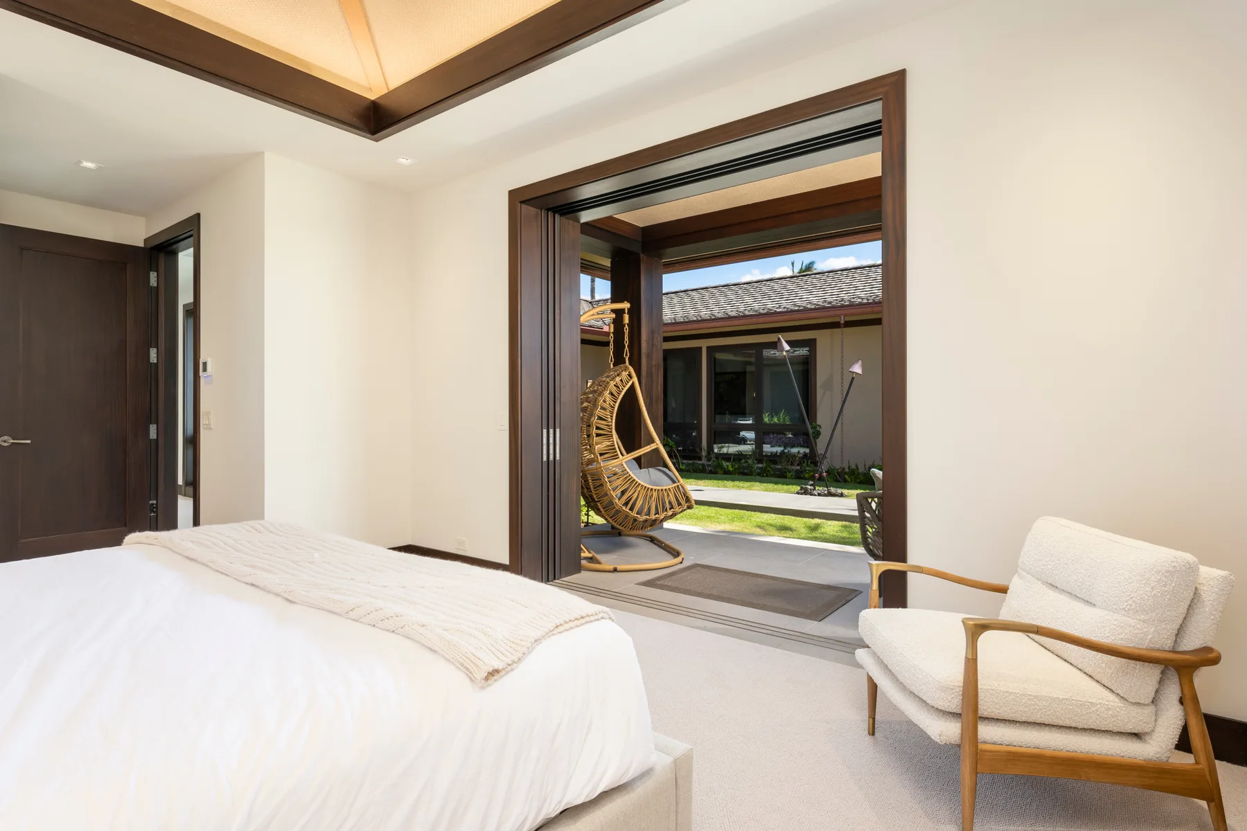 Un dormitorio luminoso da a un patio, con una cama y asientos acolchados.