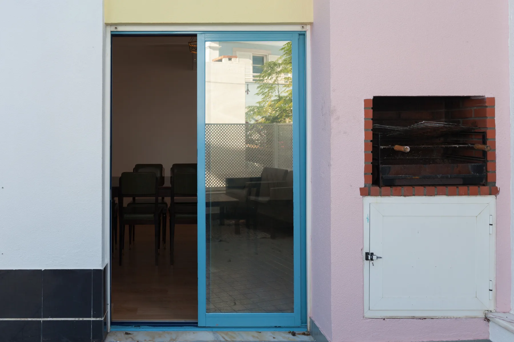 A patio entrance with a blue-framed sliding glass door and a built-in grill.
