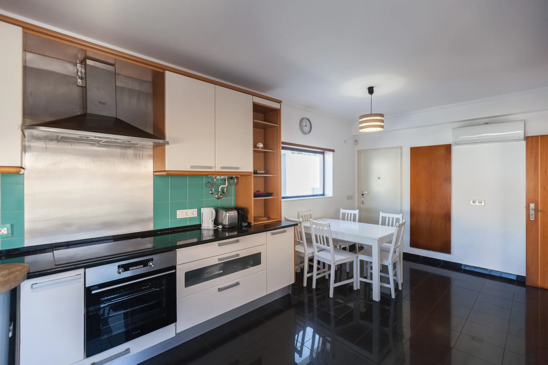 A bright kitchen and dining area with white cabinets and a dining table.