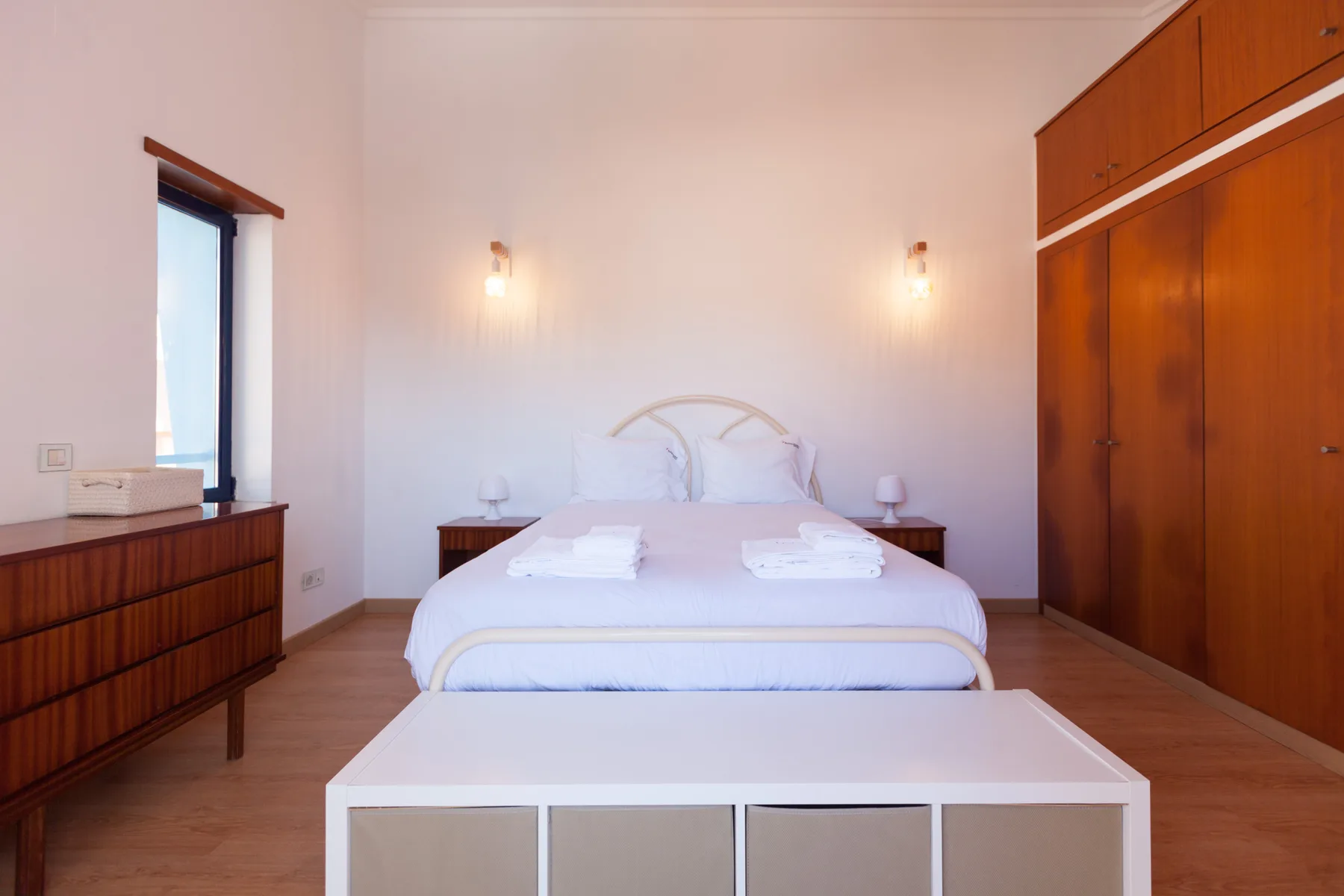 A bedroom with a bed, bedside tables, and wooden wardrobes.