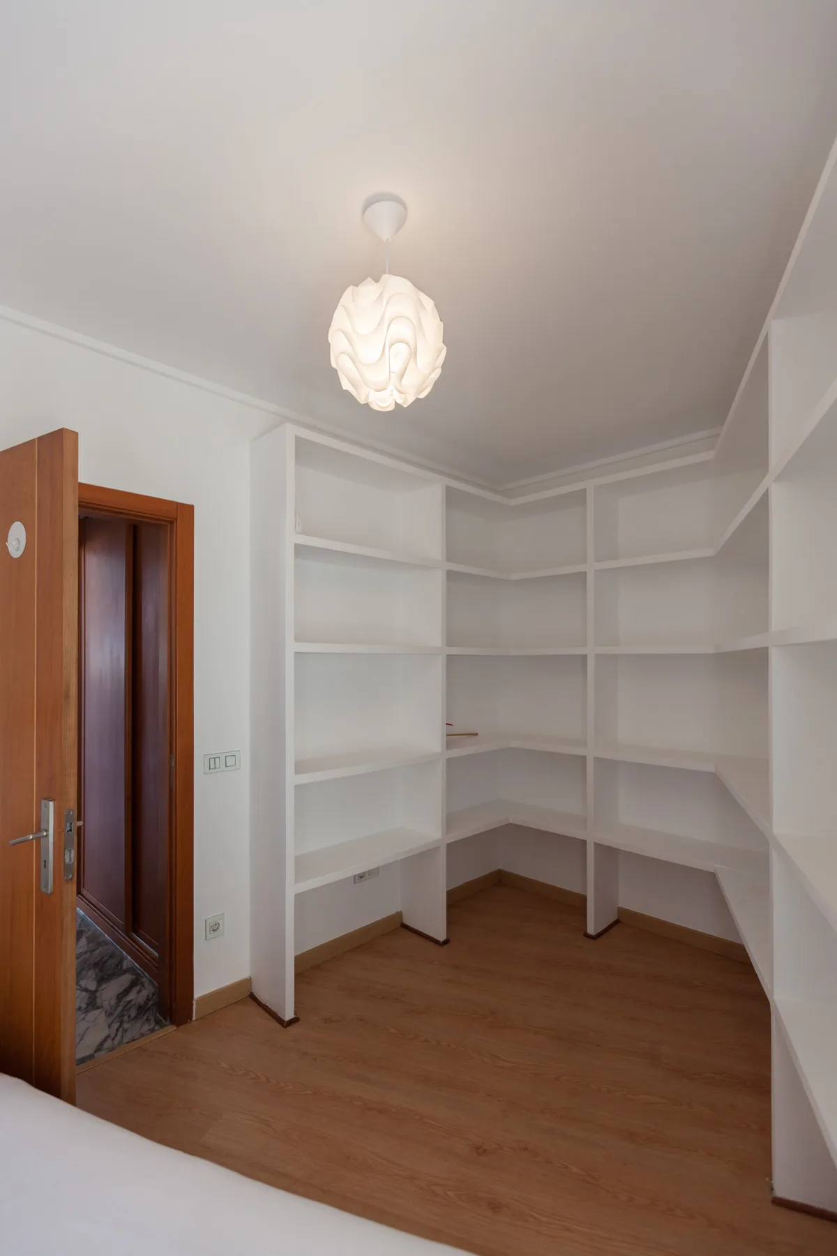 An empty room with built-in shelving and wood flooring.