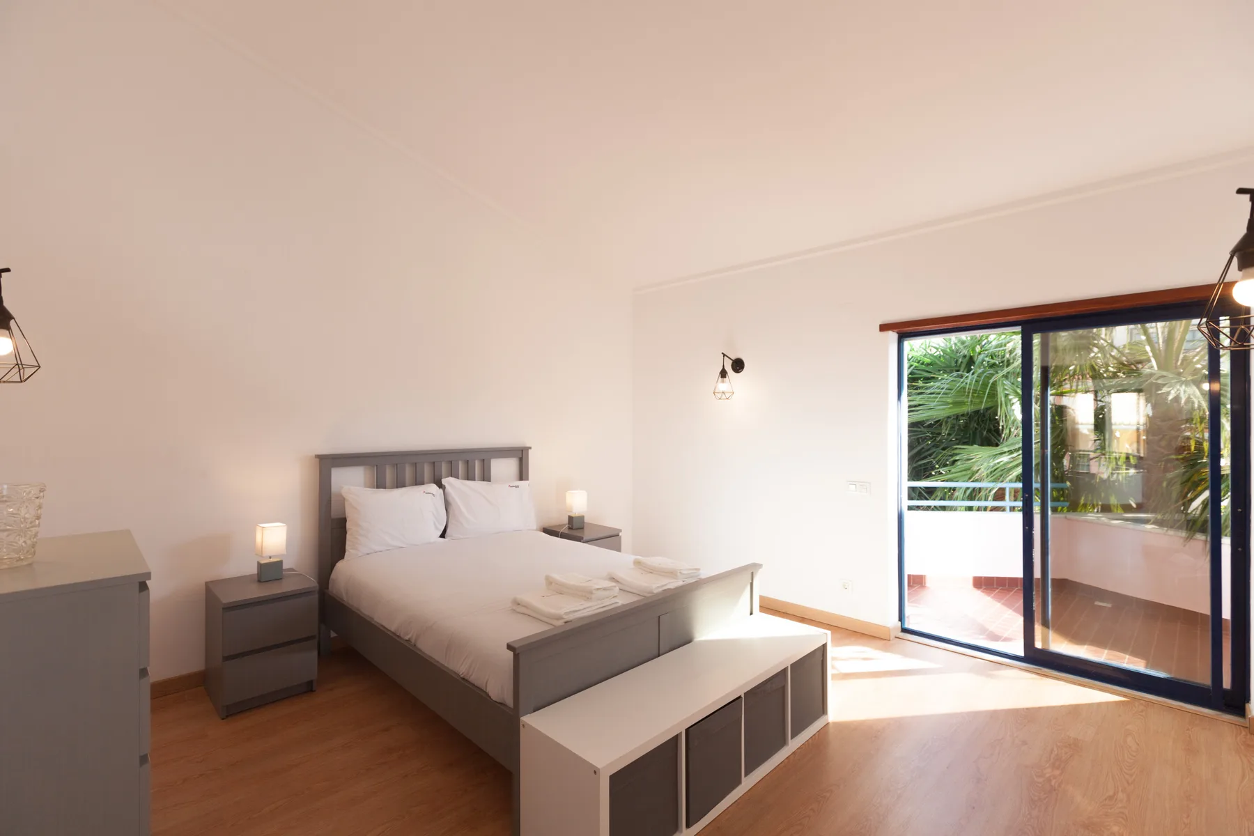A bright bedroom with a bed and sliding glass doors opening onto a terrace.