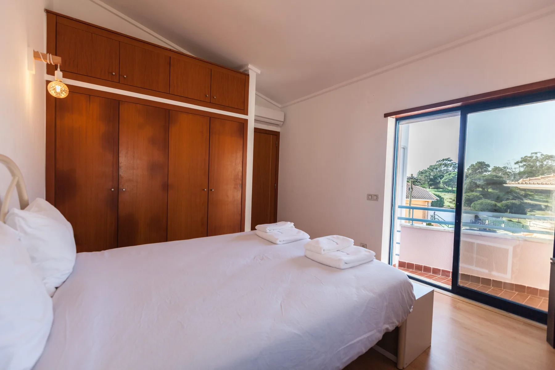A bedroom with a bed beside sliding glass doors opening onto a balcony.