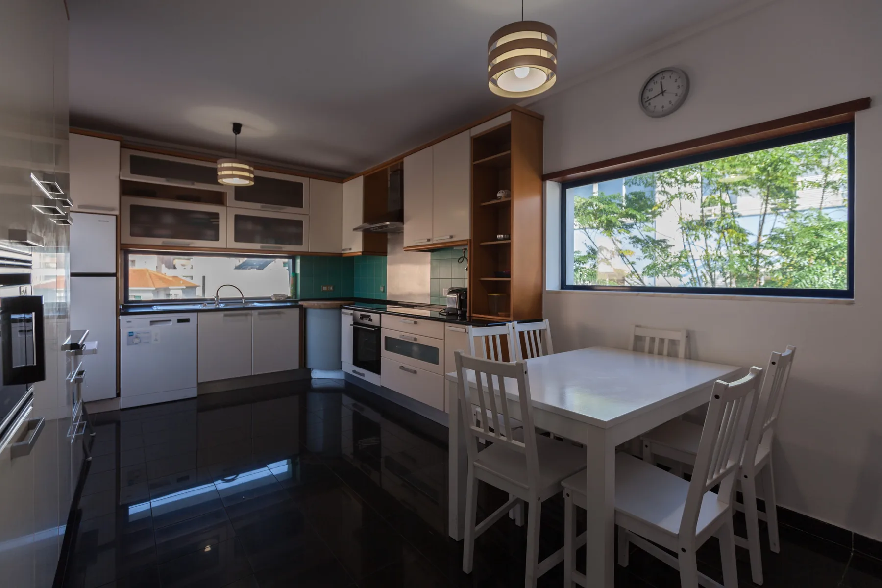 A modern kitchen with a dining table beside a large window.