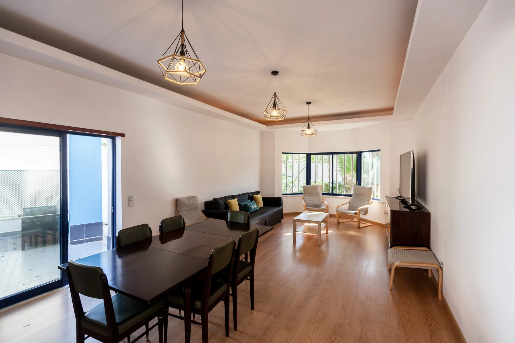 A bright living and dining room with a long table and seating.