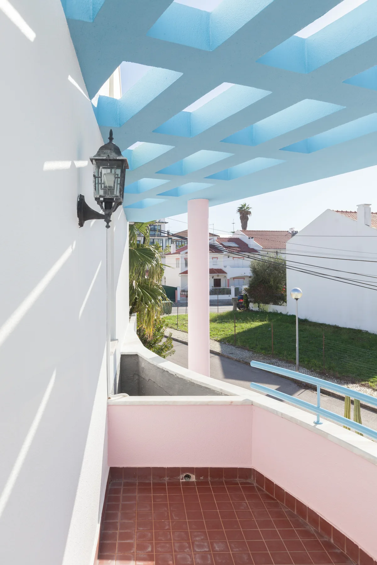 A small tiled balcony opens onto a sunny view of nearby houses.