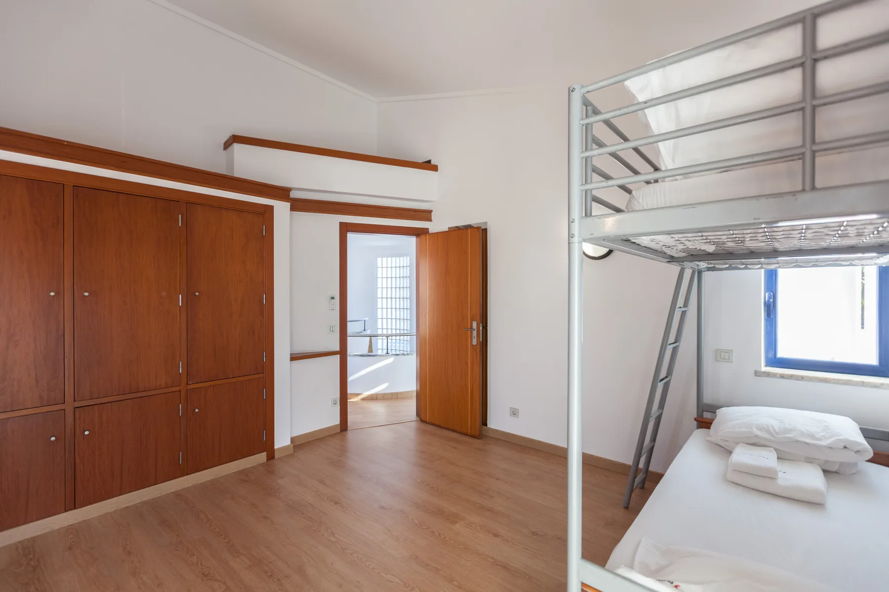 A bedroom with a metal bunk bed and wooden cabinets.