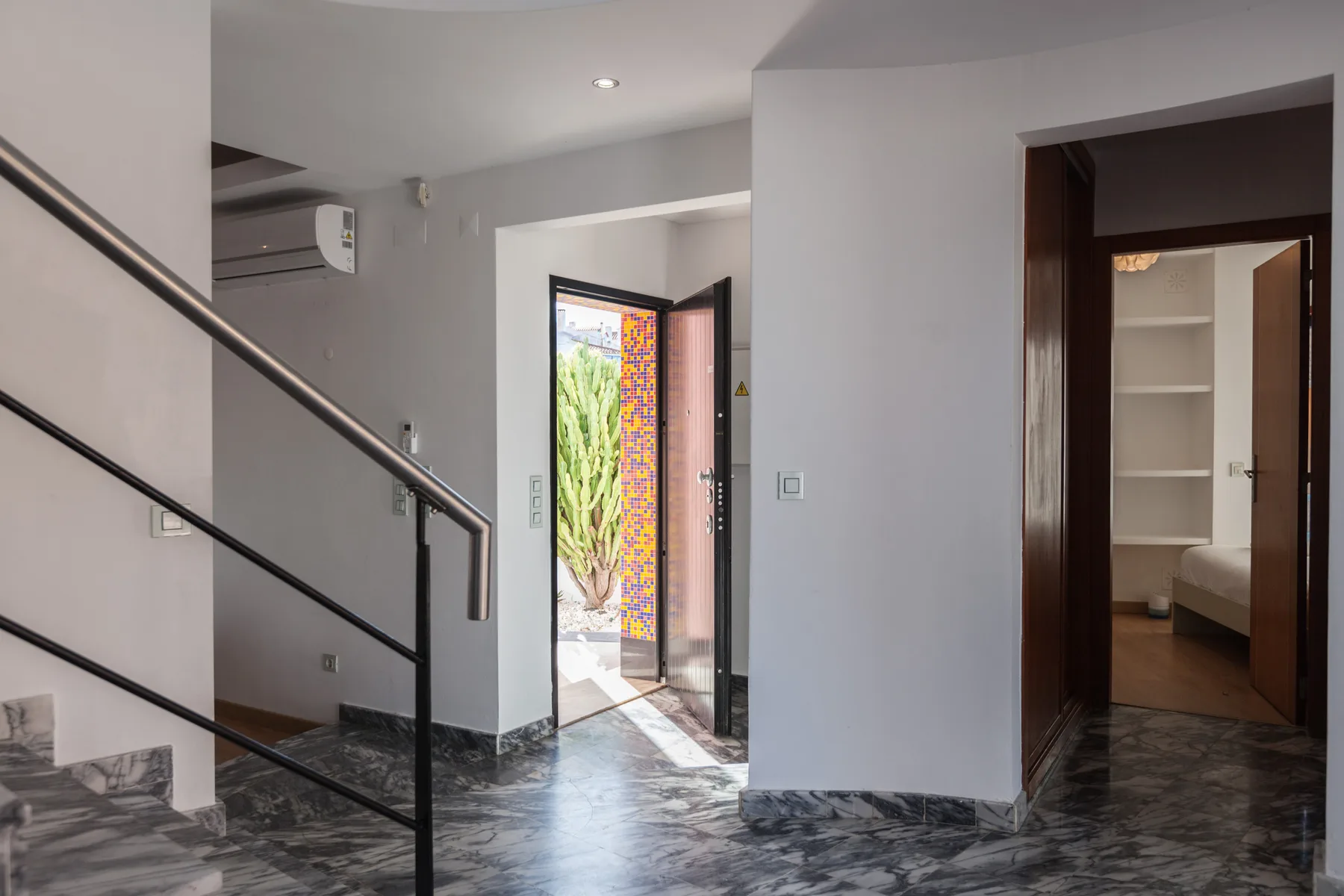 An interior entryway with a staircase and an open doorway to a bedroom.