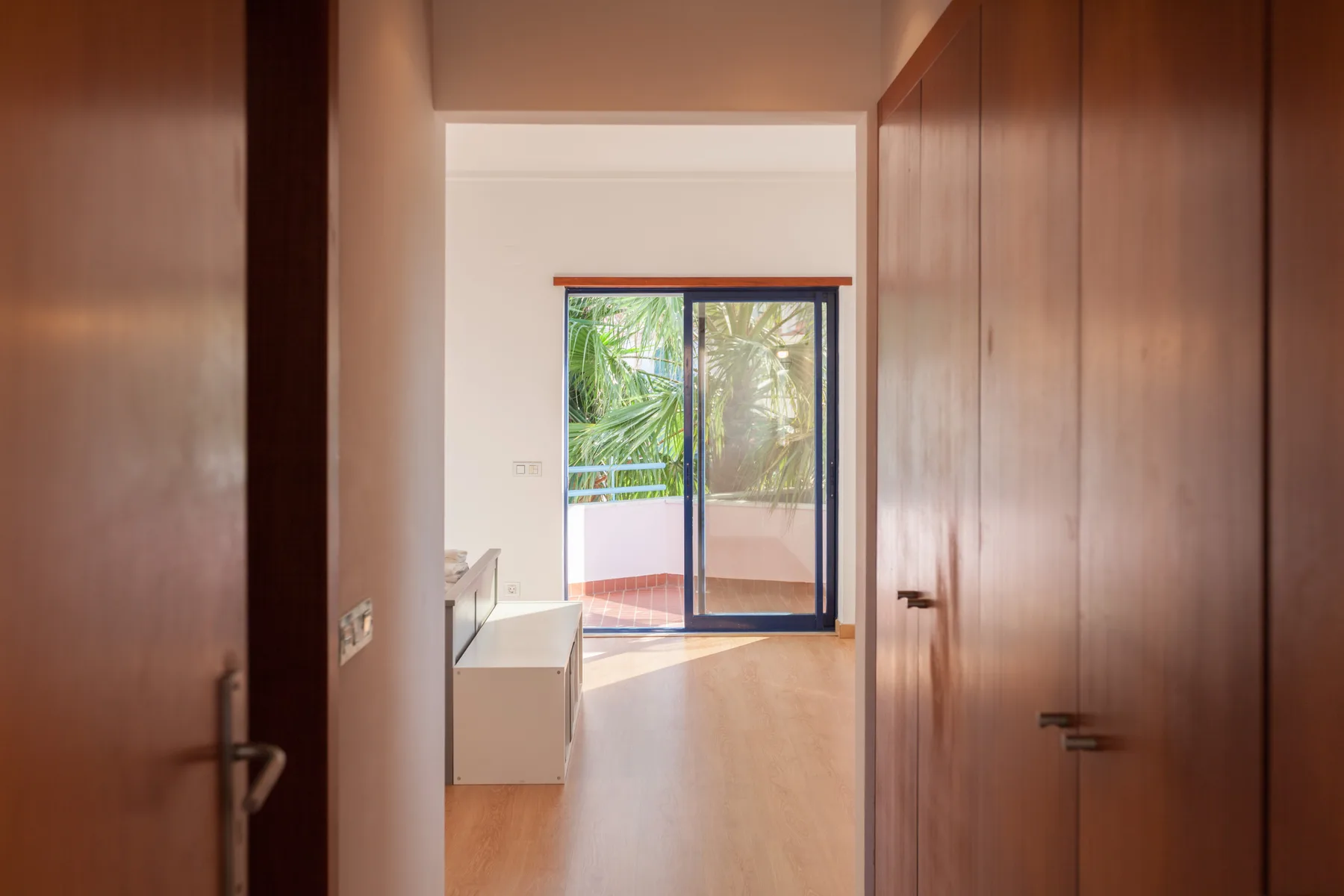 A bright interior hallway leads to a sliding glass door overlooking greenery.