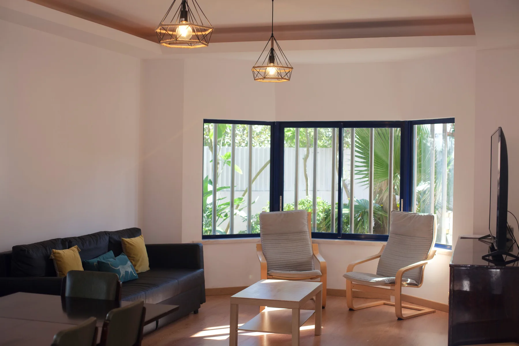 Living room with seating arranged around a coffee table beside large windows.