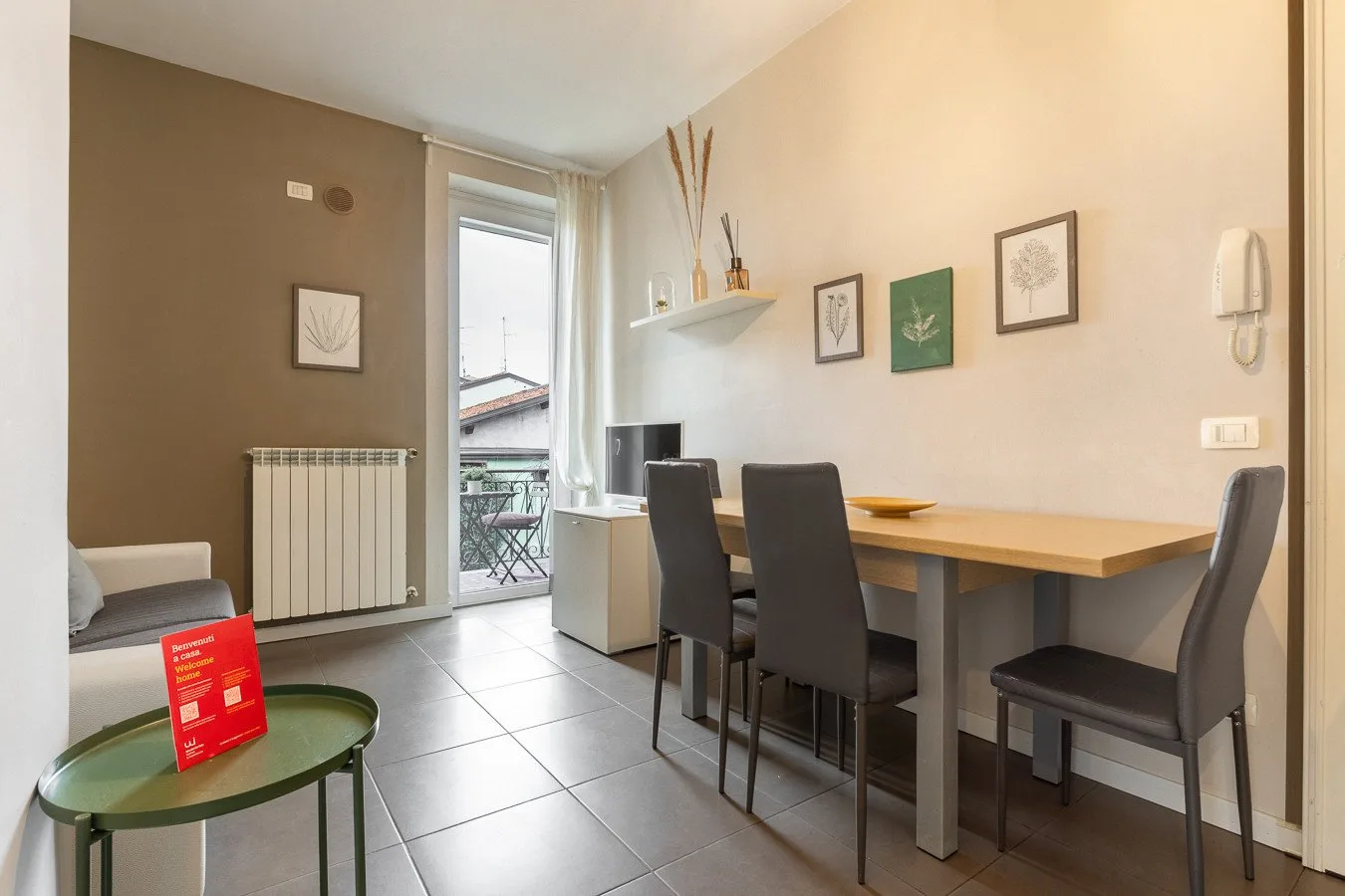 Comedor con una mesa larga y asientos oscuros junto a una puerta de vidrio.