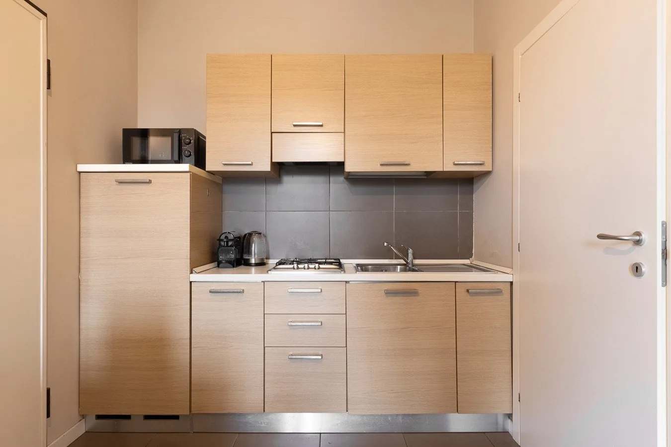 Una cocina compacta con gabinetes de madera clara, una estufa y una encimera.