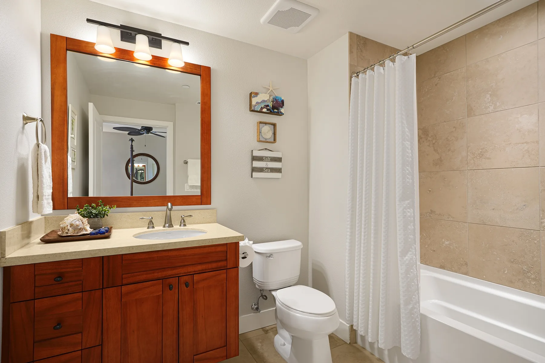A bathroom with a wood vanity, toilet, and bathtub behind a shower curtain.