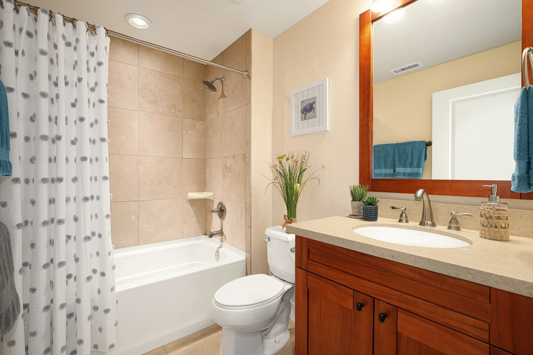 A bathroom with a bathtub, shower curtain, toilet, and vanity.