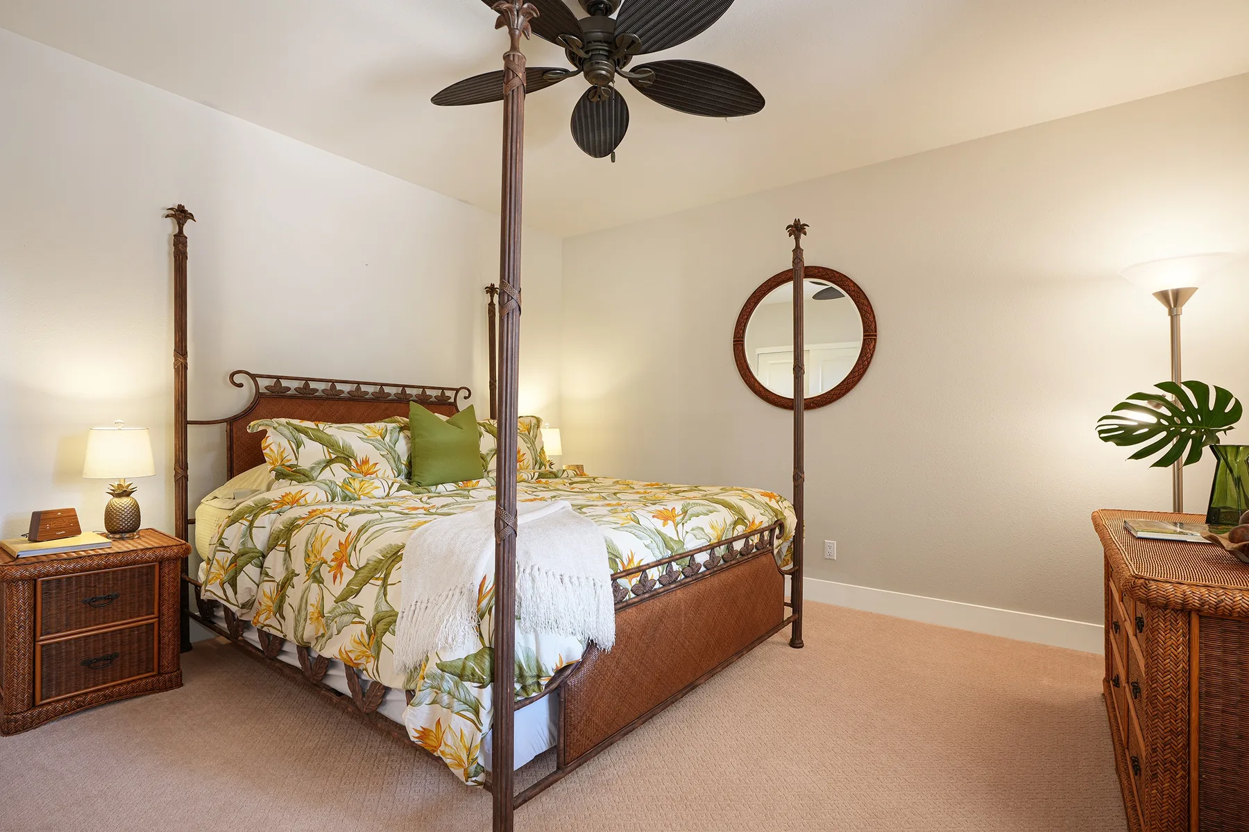 A bedroom with a canopy bed, patterned bedding, and a round wall mirror.