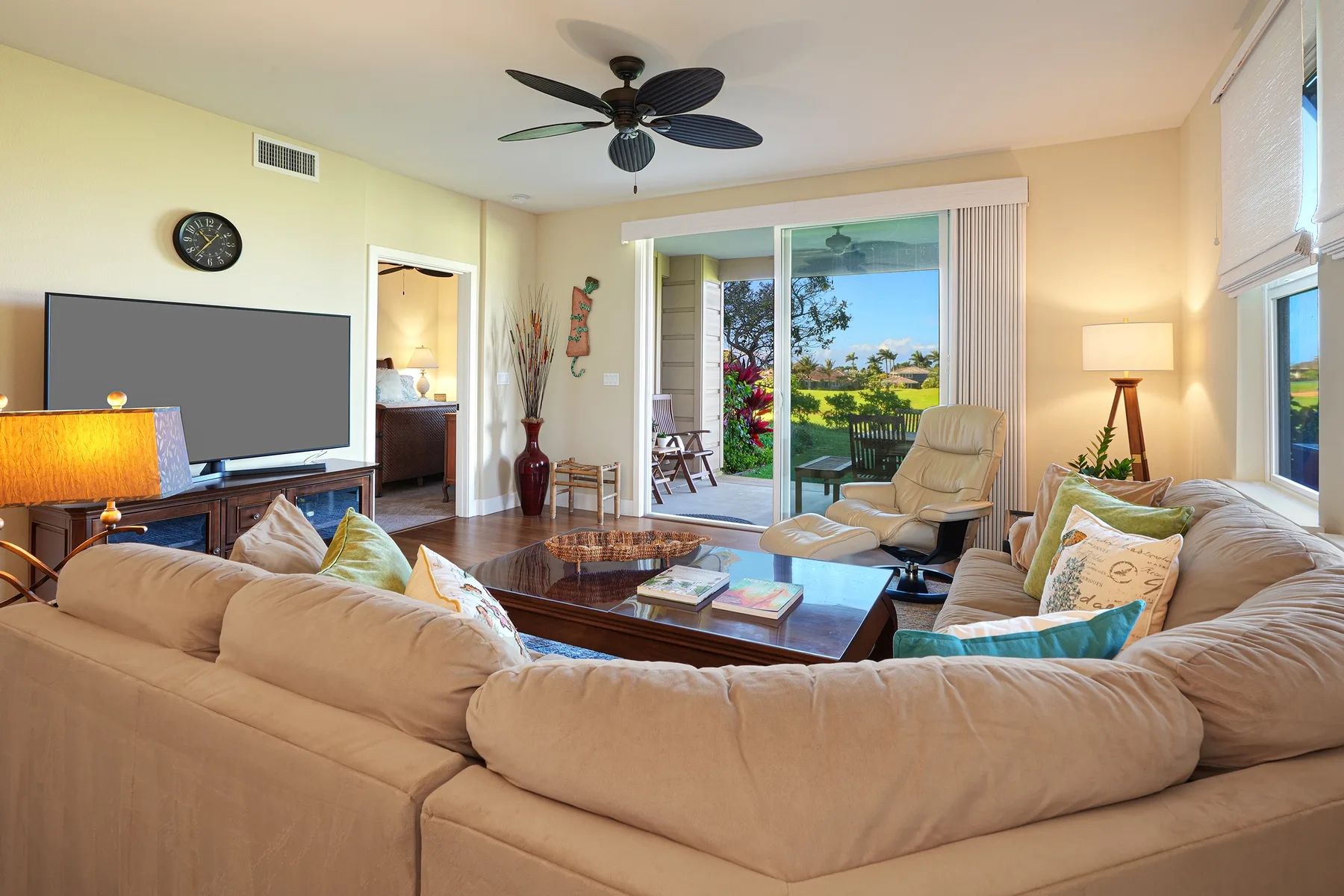 A bright living room with a sectional sofa and sliding glass doors opening to a garden.