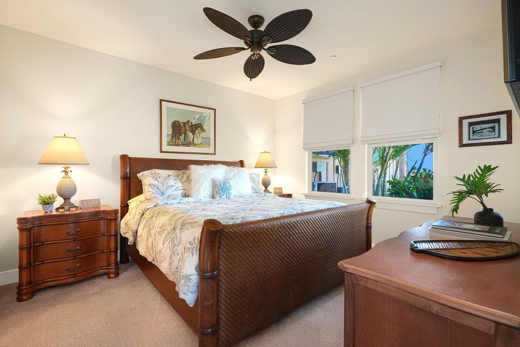 A bedroom with a wooden bed, bedside tables, and windows overlooking greenery.