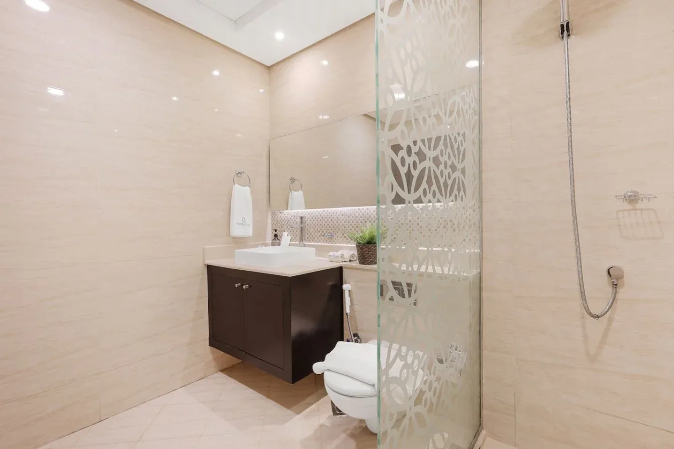 Un baño luminoso con lavabo, inodoro y mampara de ducha de vidrio.