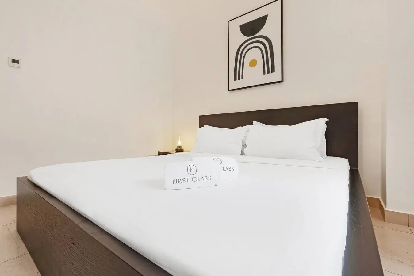 Un dormitorio con una cama bien tendida bajo un cuadro enmarcado.