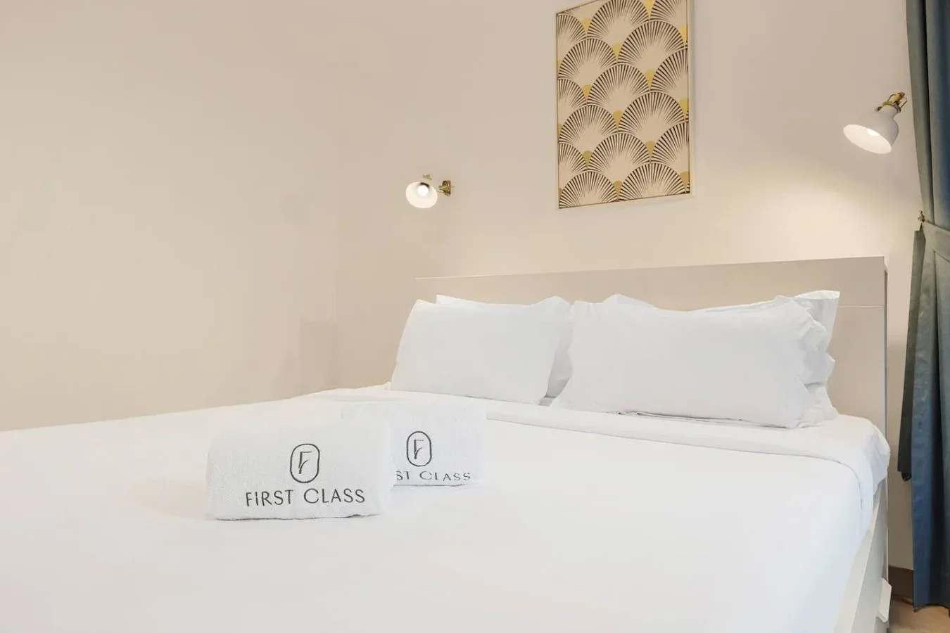Una cama bien tendida con ropa de cama blanca ocupa este dormitorio.
