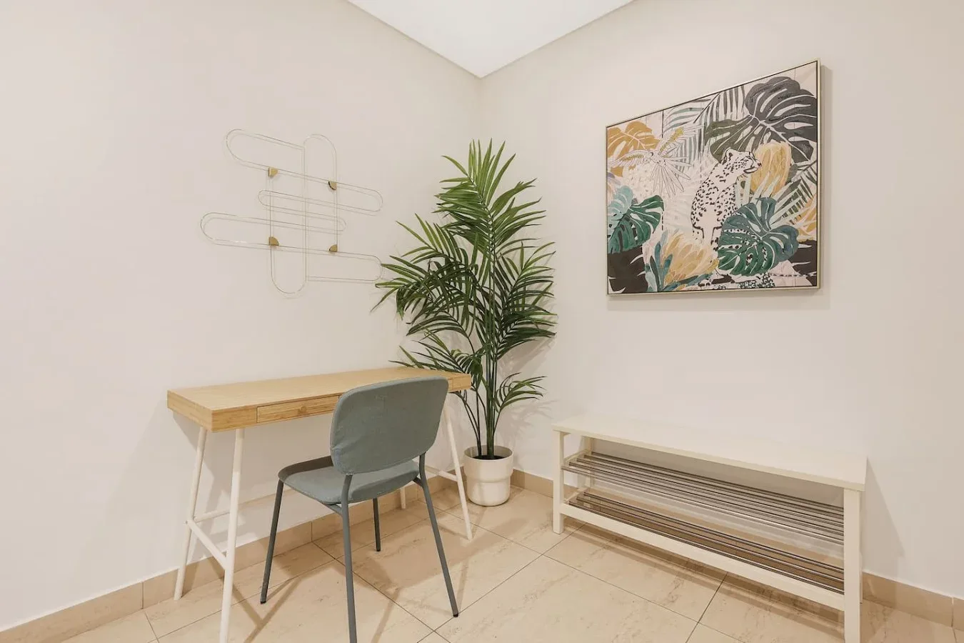 Una habitación luminosa con escritorio, asiento, planta en maceta y arte colorido en la pared.