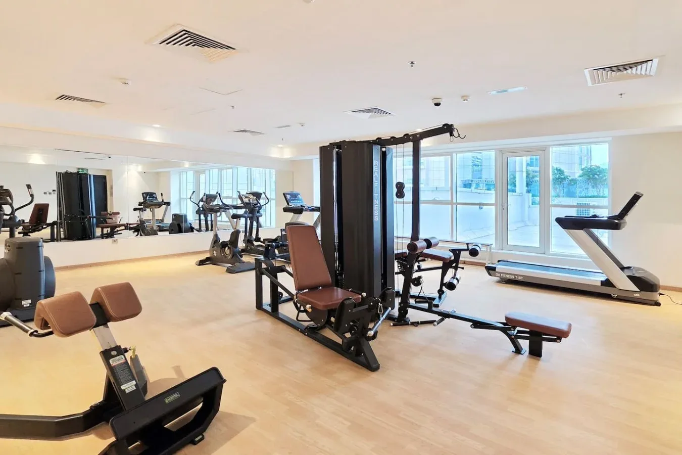 Una sala de entrenamiento con máquinas de ejercicio, pesas y ventanales.