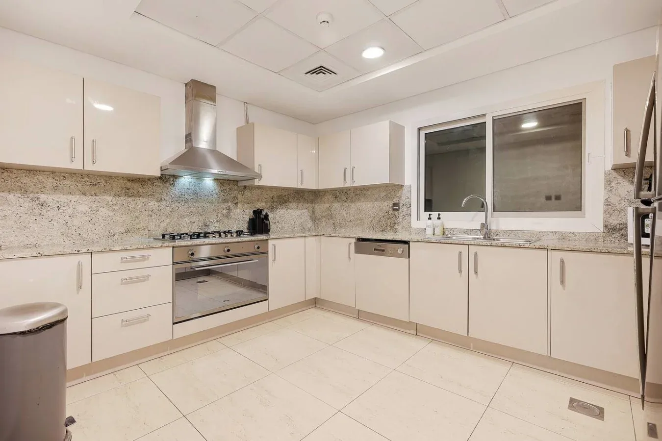 Una cocina luminosa con gabinetes claros, una estufa y un fregadero bajo la ventana.