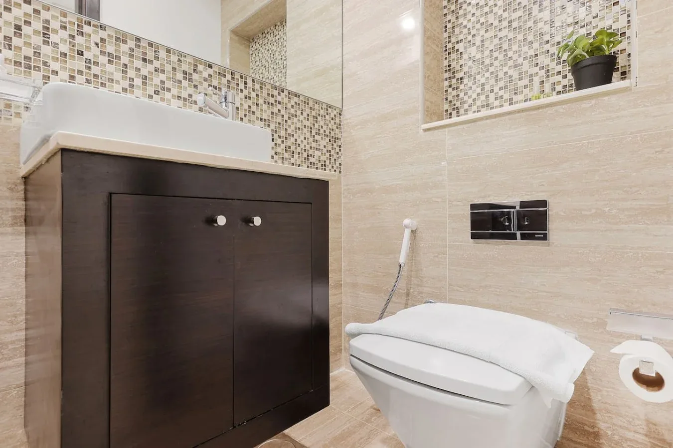 Un baño con un mueble oscuro, lavabo e inodoro.