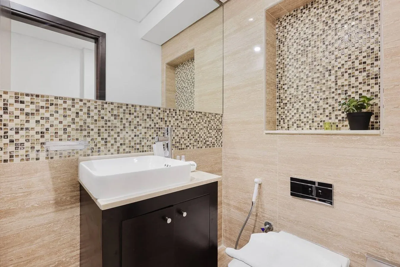 Un baño con lavabo blanco, paredes de azulejos y un inodoro.