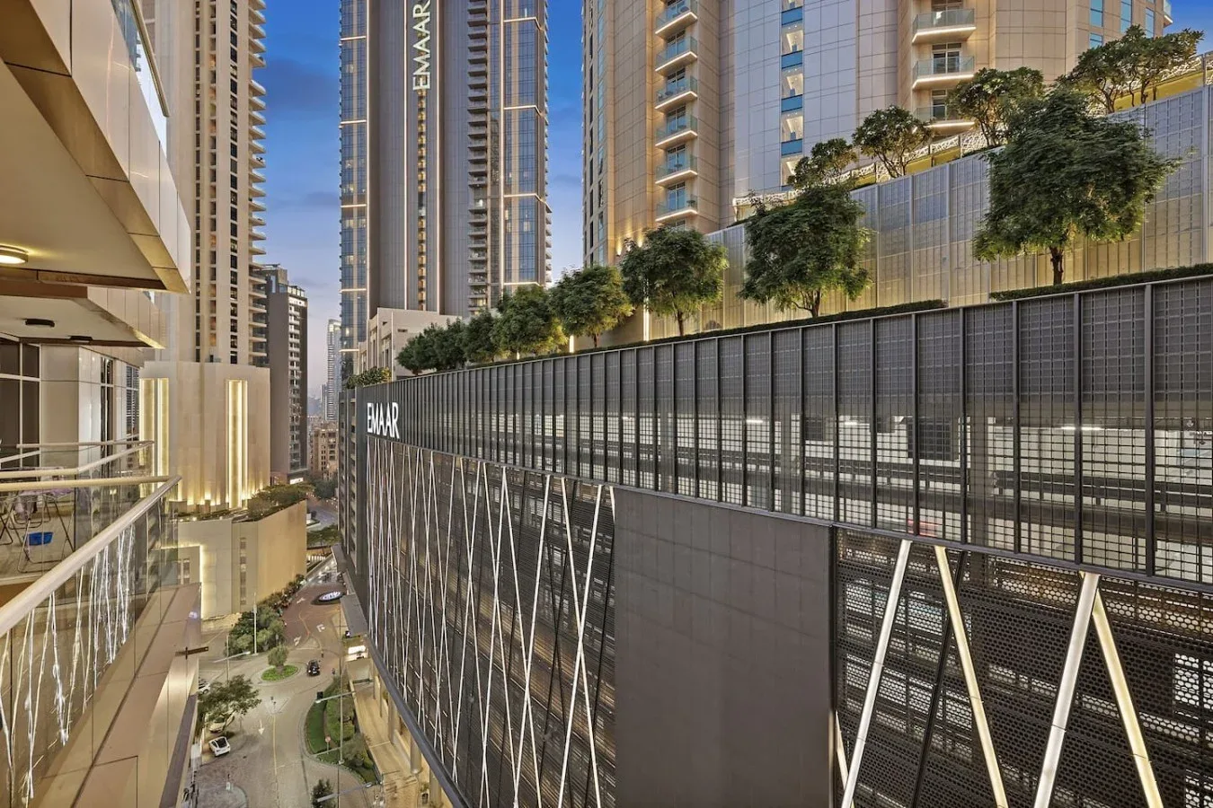 Una calle urbana pasa entre edificios altos, junto a una terraza ajardinada.