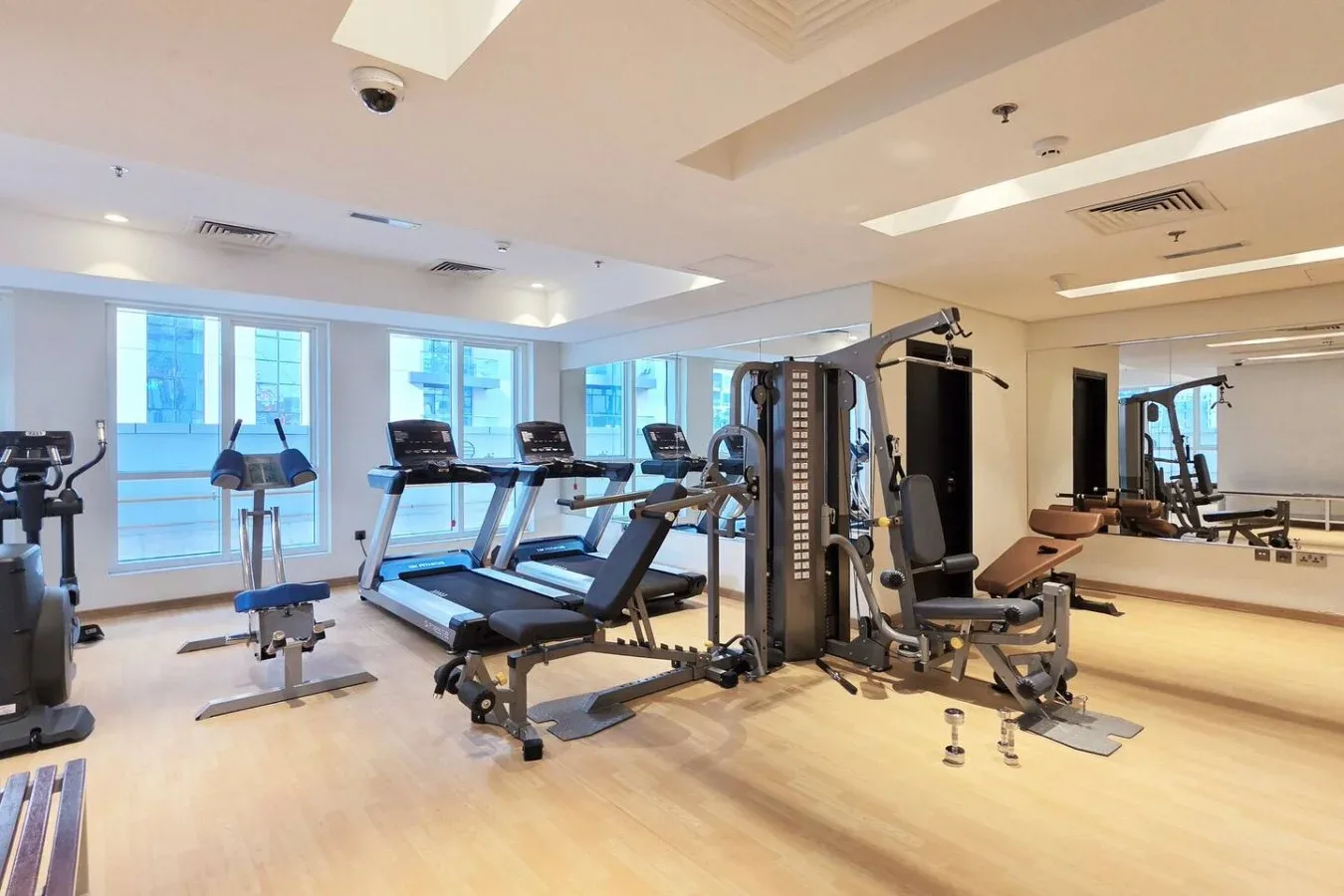 Un gimnasio con cintas de correr, máquinas de pesas y ventanales.