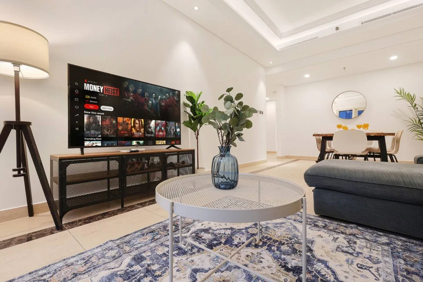 Una sala luminosa con televisor, asientos y un comedor.