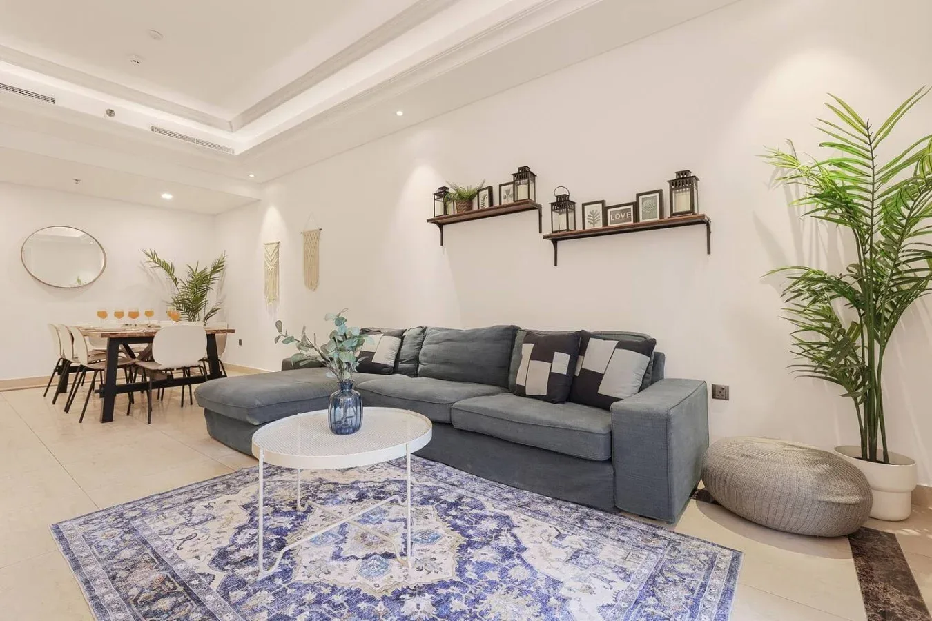 Una luminosa sala de estar y comedor con asientos grises, una alfombra estampada y una mesa de comedor.