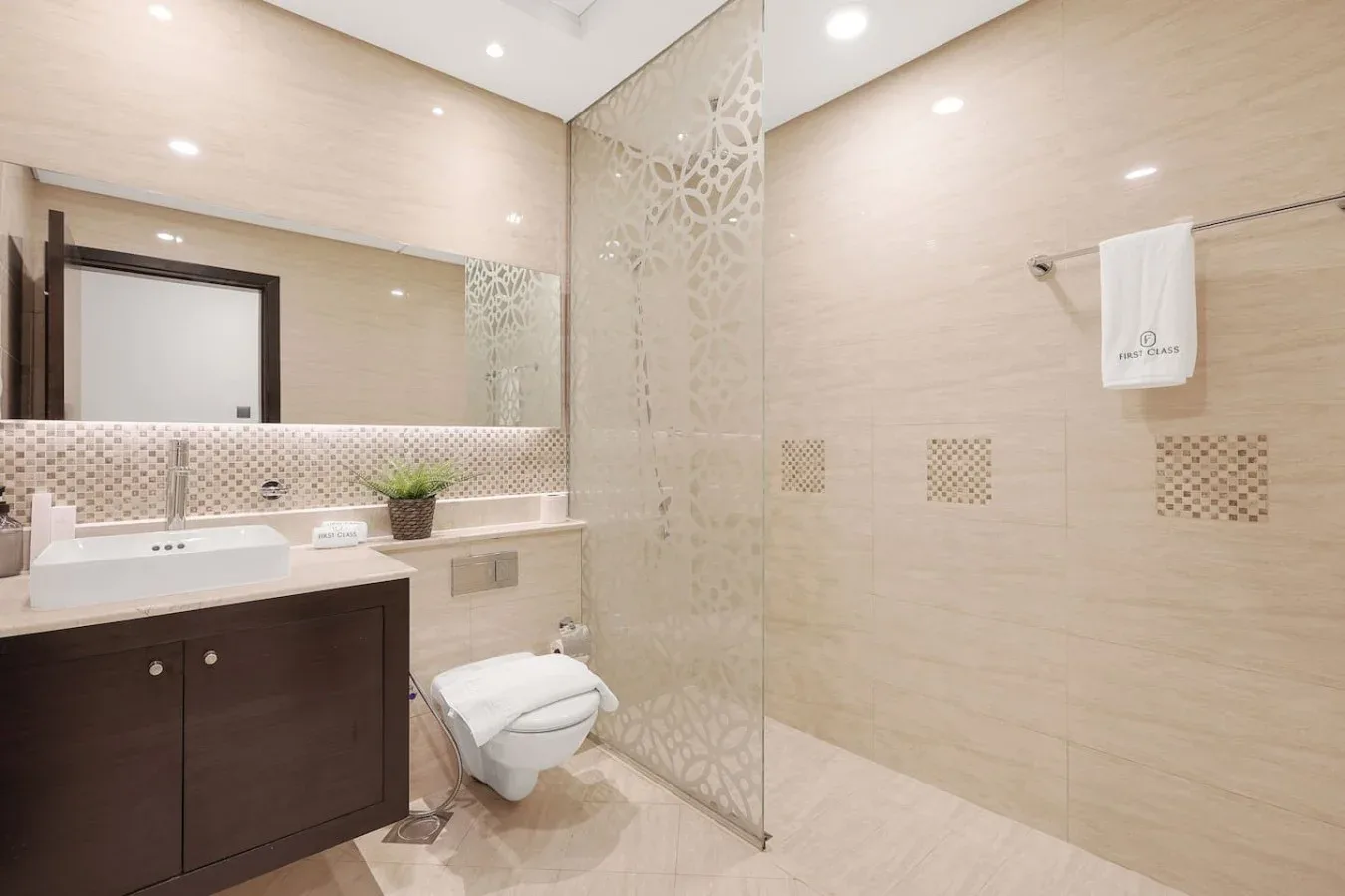 Un baño luminoso con un tocador largo, inodoro y ducha de vidrio.