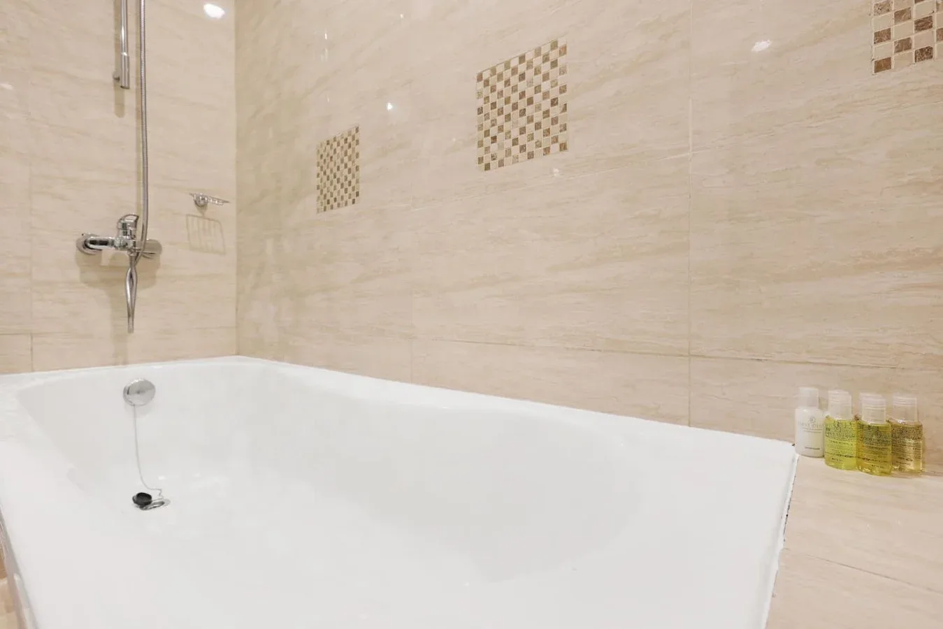 Una bañera está junto a una pared de azulejos con una ducha instalada.