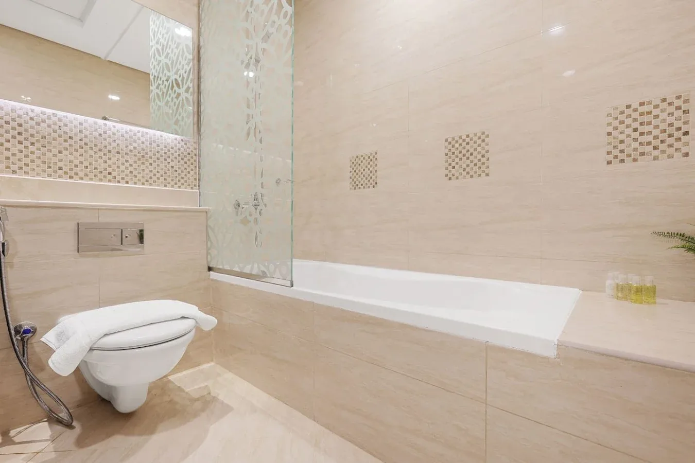 Un baño luminoso con bañera, mampara de vidrio e inodoro.