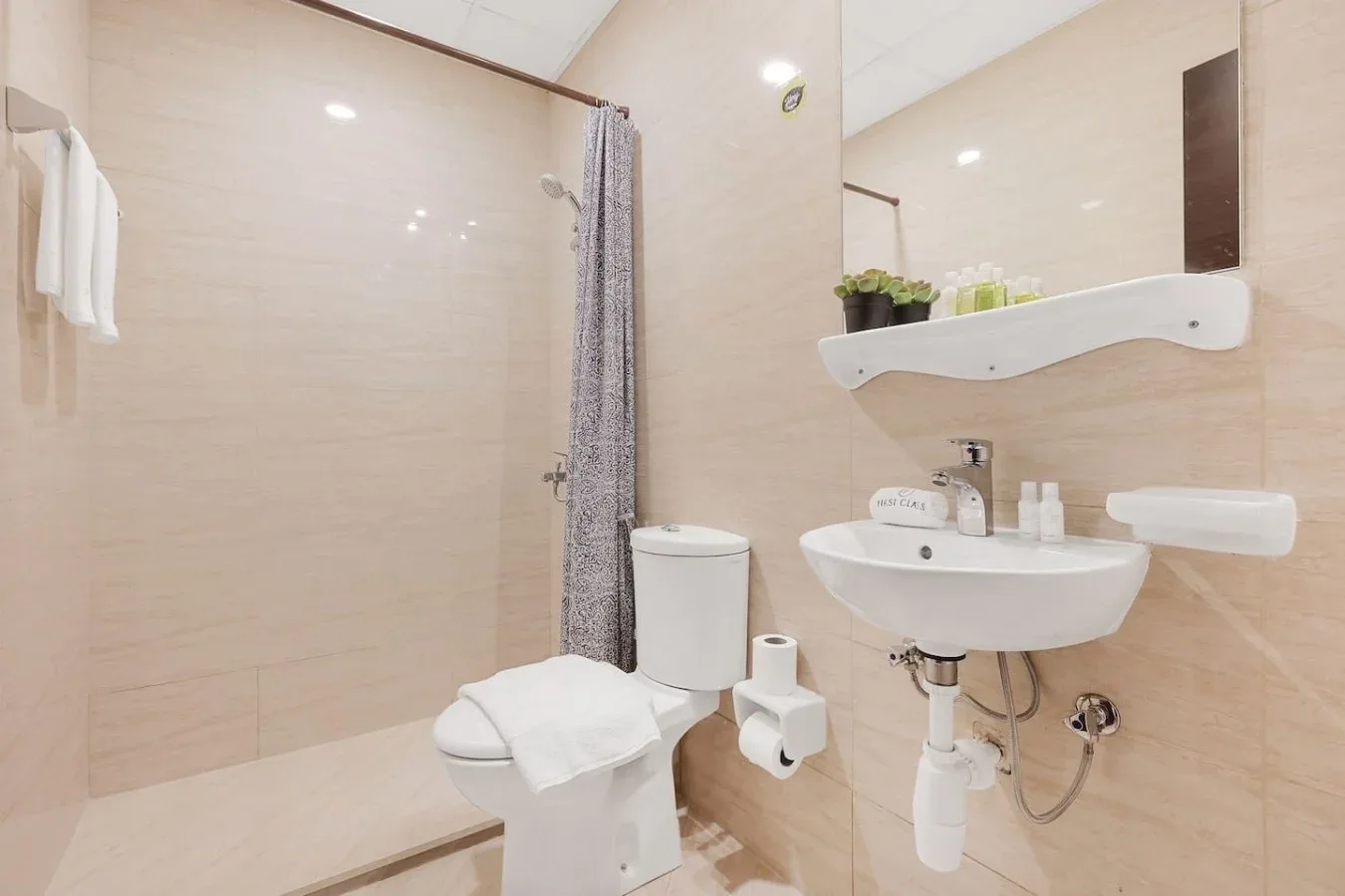 Un baño luminoso con lavabo, inodoro y zona de ducha.
