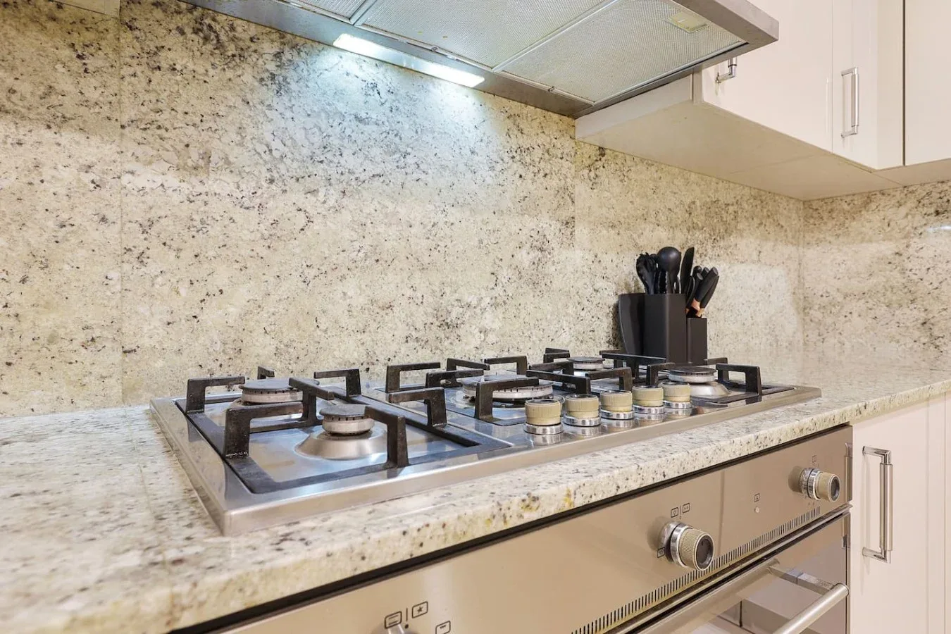 Una placa de cocina está debajo de una campana extractora de acero inoxidable.