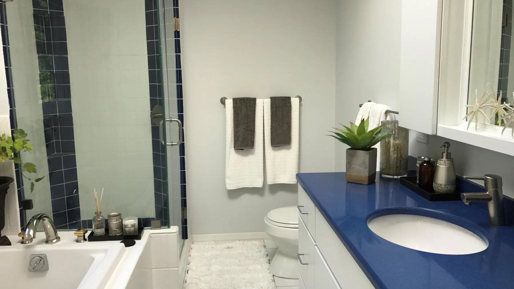 A bathroom with a bathtub, toilet, and blue vanity countertop.